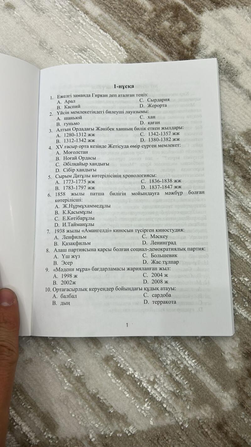 Видна страница книги с вопросами с множественным выбором на казахском языке, охватывающая темы истории и культуры, включая вопросы об исторических личностях, периодах времени и культурных программах.