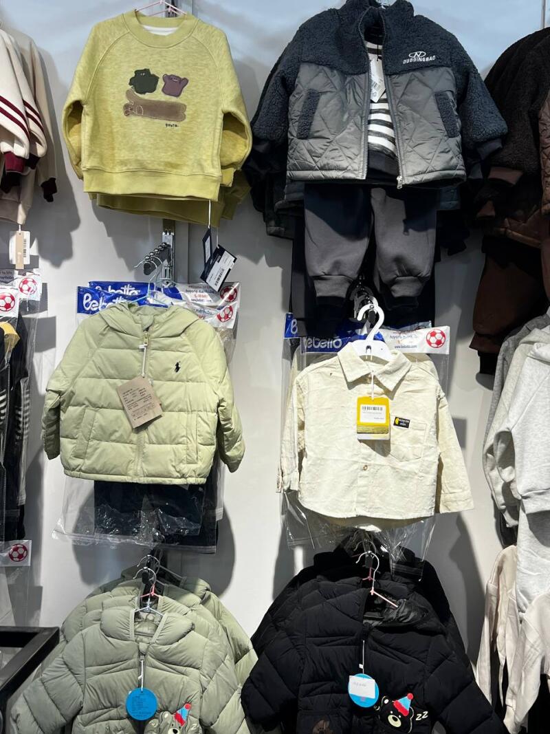 A display of children's clothing, including sweatshirts, jackets, and pants in various colors such as yellow, grey, and black.
