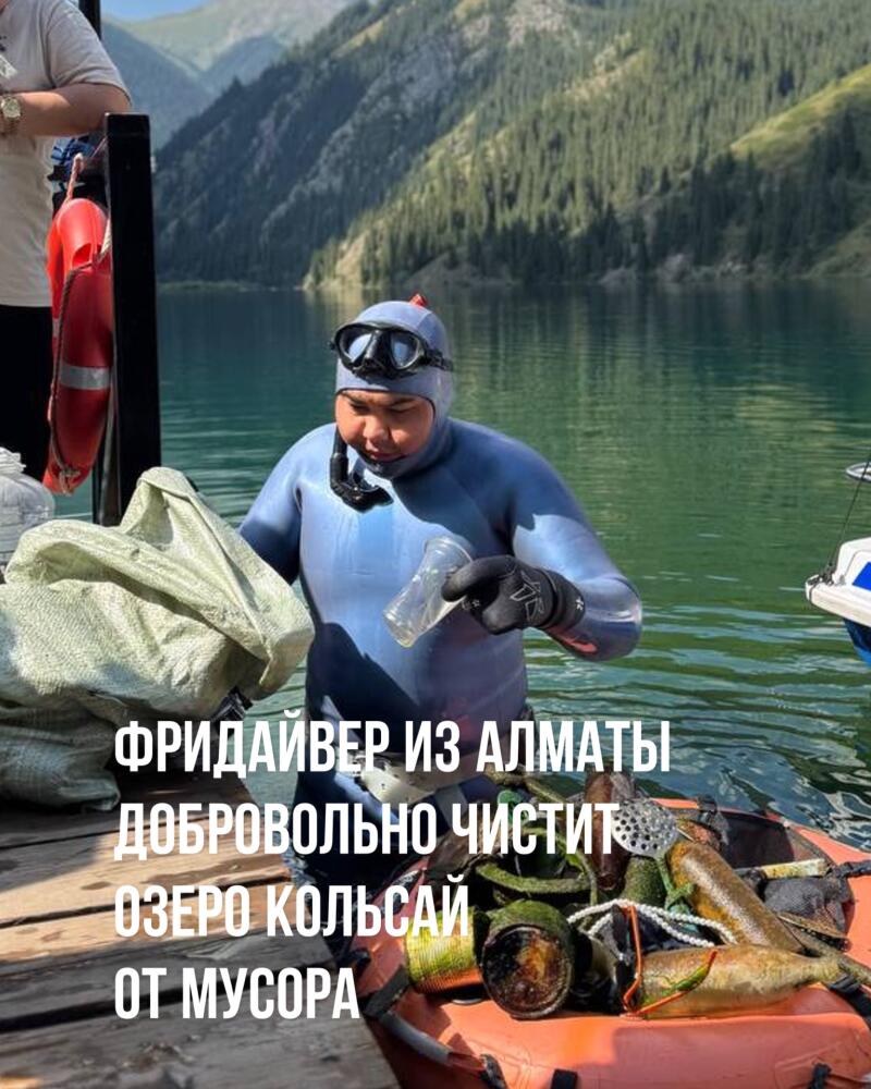 A man in a wetsuit and diving mask is holding a plastic bottle, standing next to a pile of trash in a boat on a lake; the text reads, "FREEDIVER FROM ALMATY VOLUNTARILY CLEANS THE KOLSAI LAKE FROM TRASH."