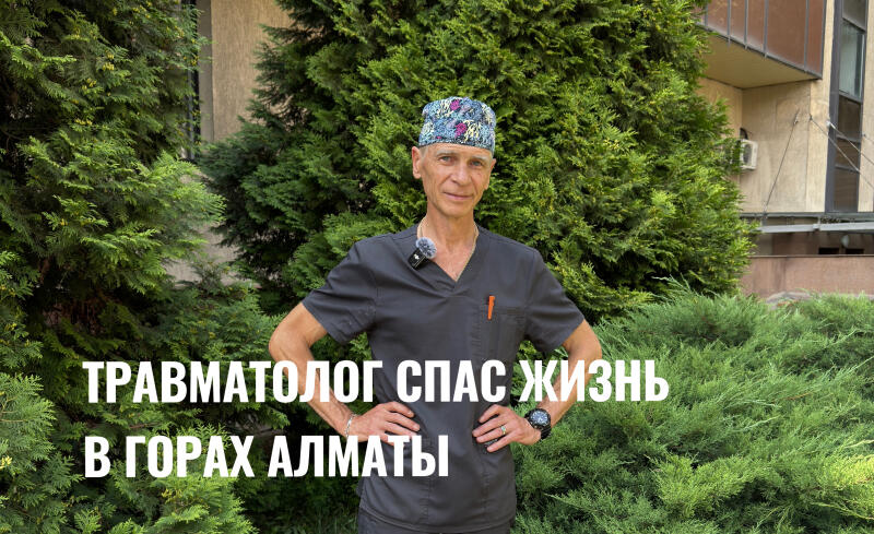 A man in a medical uniform and cap stands with his hands on his hips in front of green trees; superimposed text reads "ТРАВМАТОЛОГ СПАС ЖИЗНЬ В ГОРАХ АЛМАТЫ" (Traumatologist saved a life in the mountains of Almaty).