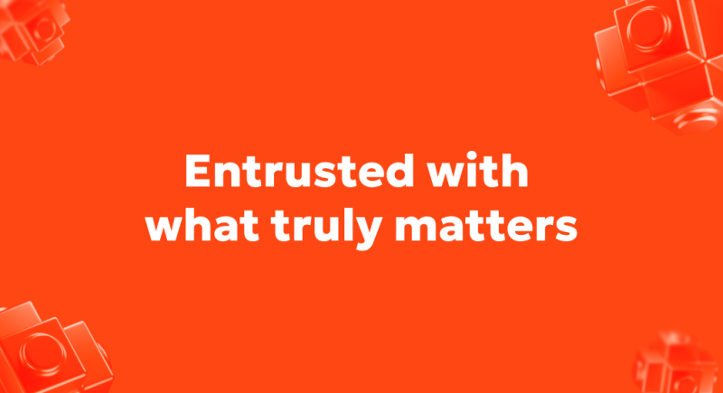 На изображении оранжевый фон с белым текстом, гласящим: «Entrusted with what truly matters» (Доверено то, что действительно важно). Также присутствуют размытые оранжевые геометрические фигуры с маленькими кругами по углам.