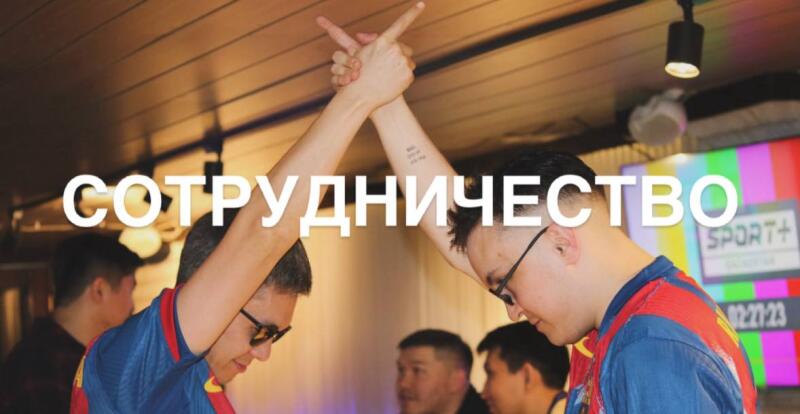 Two men in blue and red jerseys raise their arms to form an "X" shape, with the word "СОТРУДНИЧЕСТВО" (Collaboration) superimposed over the image; a screen in the background shows a test pattern and the logo "SPORT+".