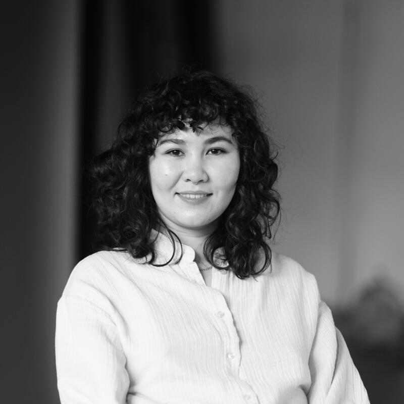 A black and white portrait of a woman with curly hair wearing a button-up shirt.