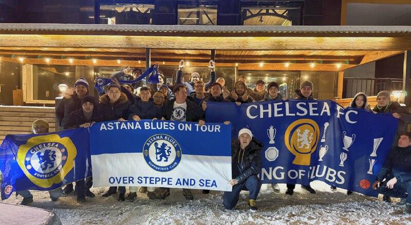 A group of people are holding Chelsea FC banners that say 'Astana Blues on Tour' and 'Over Steppe and Sea'.