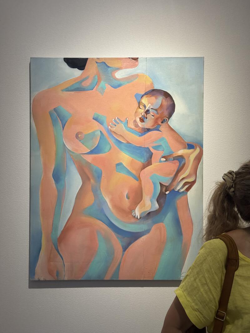 На картине изображена абстрактная фигура женщины, держащей ребенка, выполненная в персиково-голубой цветовой гамме. Форма женщины стилизована, плавные линии подчеркивают изгибы и контуры, а ребенок, с закрытыми глазами, прижался к ее рукам.
