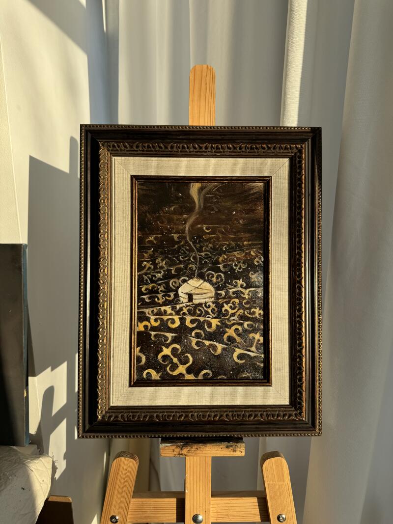 Картина маслом в витиеватой раме изображает юрту с дымом, поднимающимся из ее вершины, на фоне темно-коричневого и золотого узорчатого фона, выставленная на деревянном мольберте.