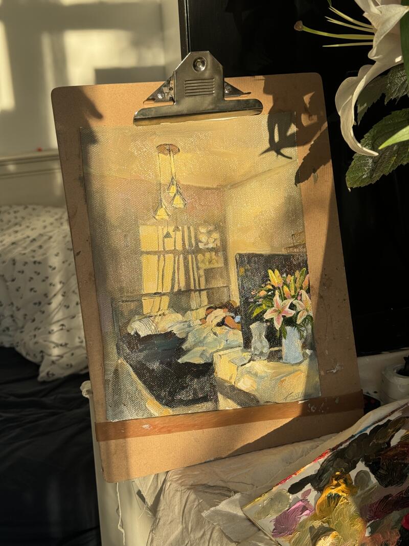 На изображении показана картина комнаты на планшете, на которой изображены кровать, прикроватный столик с цветами и книжная полка, все в теплом свете.