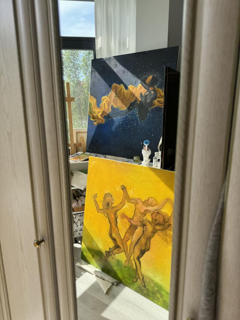 На изображении две картины, прислоненные к стене: одна с синим фоном и фигурой с желтой драпировкой, а другая с желтым фоном с несколькими фигурами.