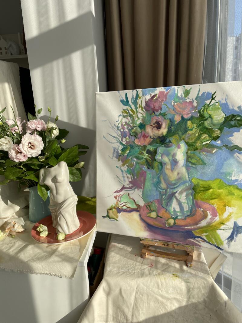 На изображении представлена композиция в стиле натюрморт с вазой розовых и белых цветов рядом с холстом, изображающим похожую цветочную композицию со статуей-вазой.