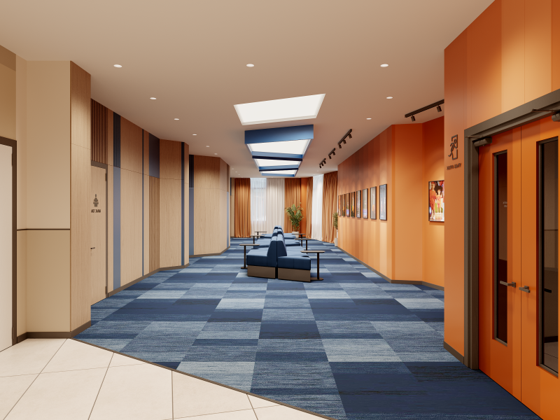 The image shows a long corridor with blue and grey square patterned carpet, a waiting area with blue couches, and orange walls with framed pictures.