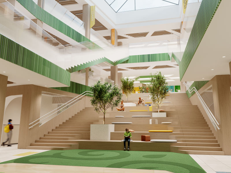 The image shows an atrium with a wide staircase that also functions as a seating area, decorated with trees and colorful banners labeled "LEARN," "CLARITY," and "STUDY".