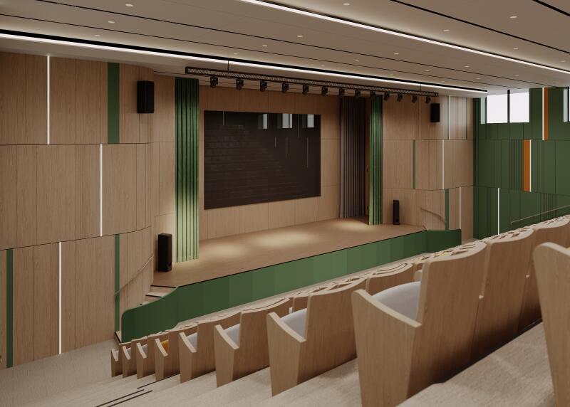 A theater hall features light wood seating facing a stage with a large screen, flanked by green curtains and speakers.