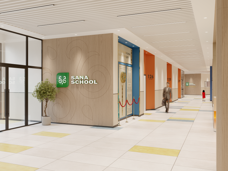 The image shows the interior of a modern school, featuring a hallway with the "SANA SCHOOL" logo on a wooden wall, a small tree, and a man walking down the hallway, with a child in the distance.