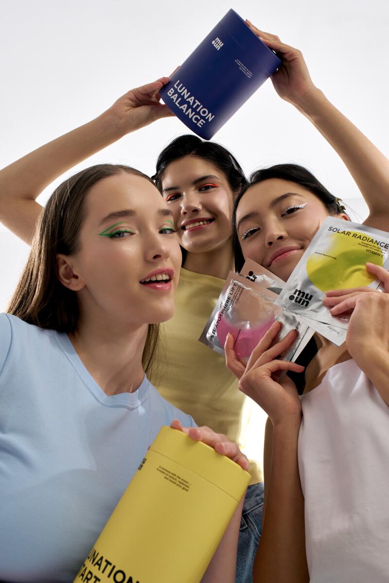 Three women display various Muun skincare products, including 'Lunation Balance,' 'Solar Radiance Vitamin C,' and 'Stratosphere Lift Collagen,' while showcasing bold, colorful eyeliner.