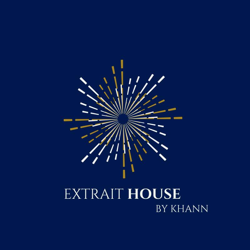 A logo on a dark blue background featuring a starburst-like graphic with radiating white and gold lines, and the text 'EXTRAIT HOUSE BY KHANN' below it.