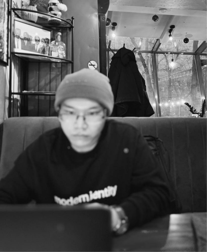 A blurry black and white shot shows a person wearing glasses and a beanie, sitting in front of a laptop, with the text "modern identity" visible on their sweatshirt.