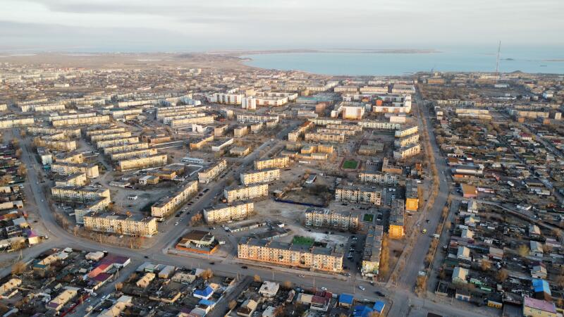 Аэрофотосъемка города с множеством зданий и дорог, расположенного рядом с большим водоемом.